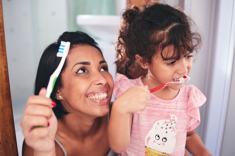 Child brushing teeth with mom- how to teach your child to be independent