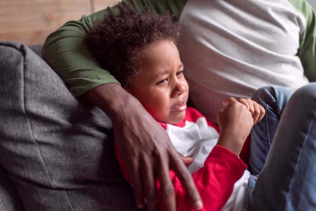 A crying boy comforted by father