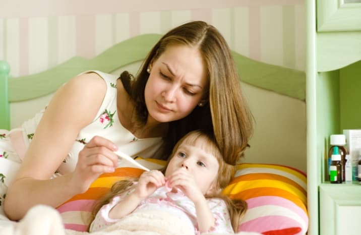 Mom checking the temperature of sick kid 