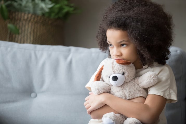 a lonely child hugging her teddy bear