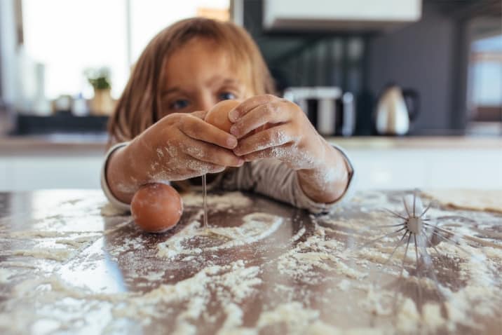 kid creating a mess baking a cake