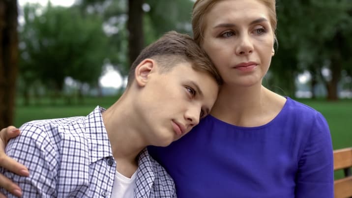 son lying on mom's shoulder and mom looks worried