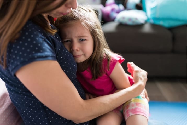 a girl sitting on her mother's lap crying