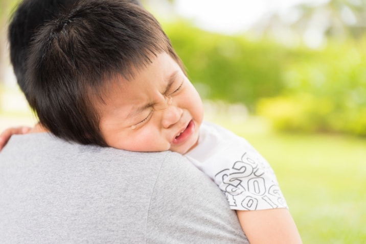 a dad hugging a toddler who is throwing a tantrum