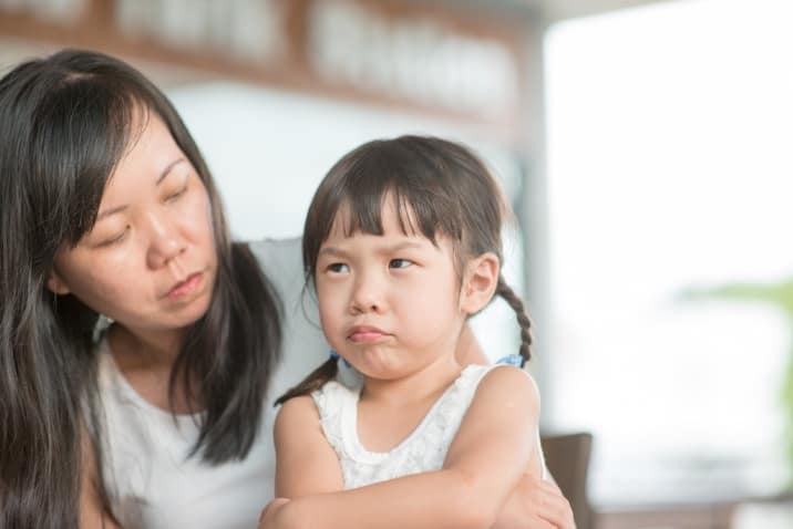 A mom sitting beside an upset toddler