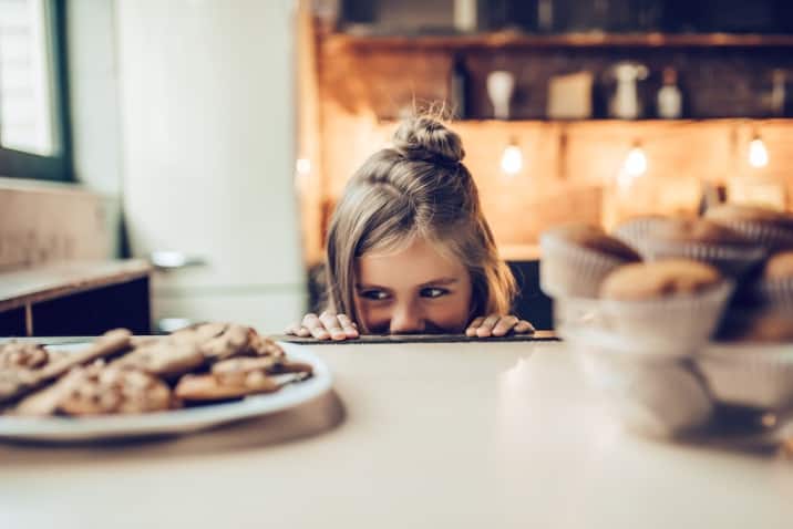 A girl trying to sneak a cookie