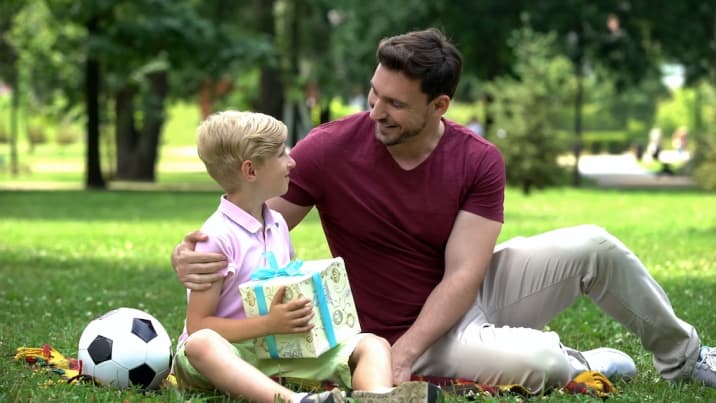 a dad giving a gift to boy - a type of positive reinforcement