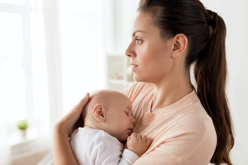 A tired and worried mom holding a baby