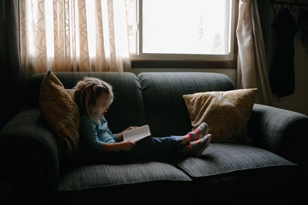 a girl reading a book on the sofa (sensitive child needing her downtime)