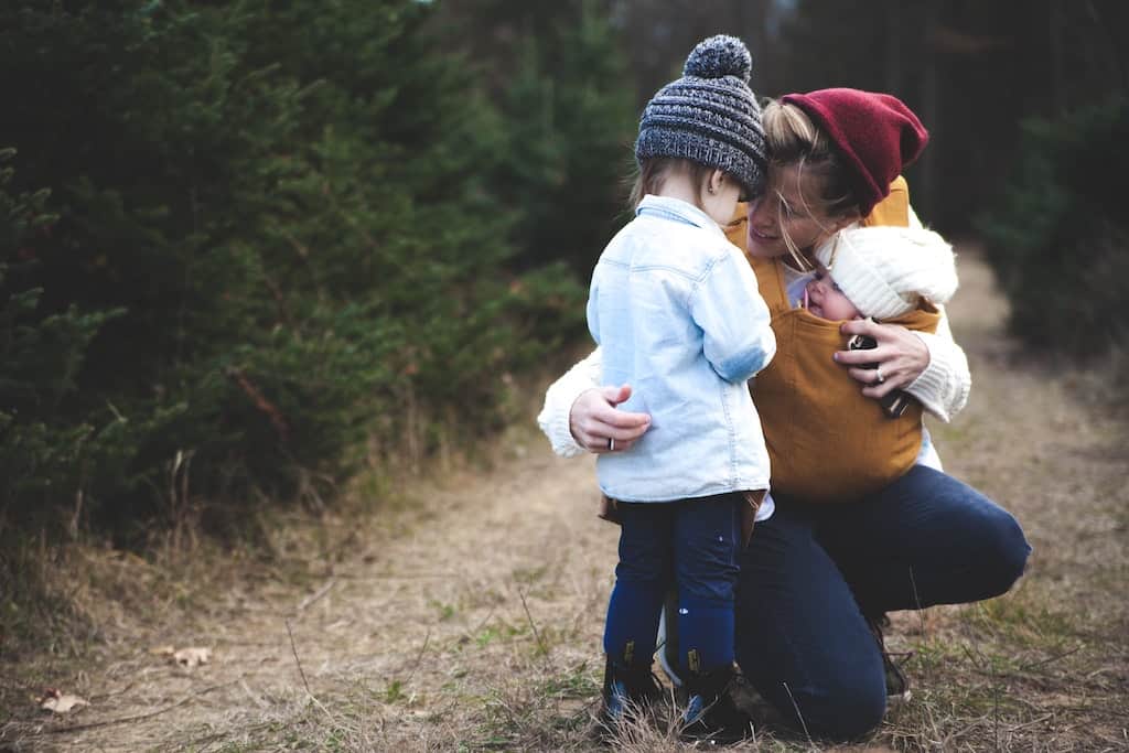 Mom hugging a child while carrying a baby-how to deal with mom burnout