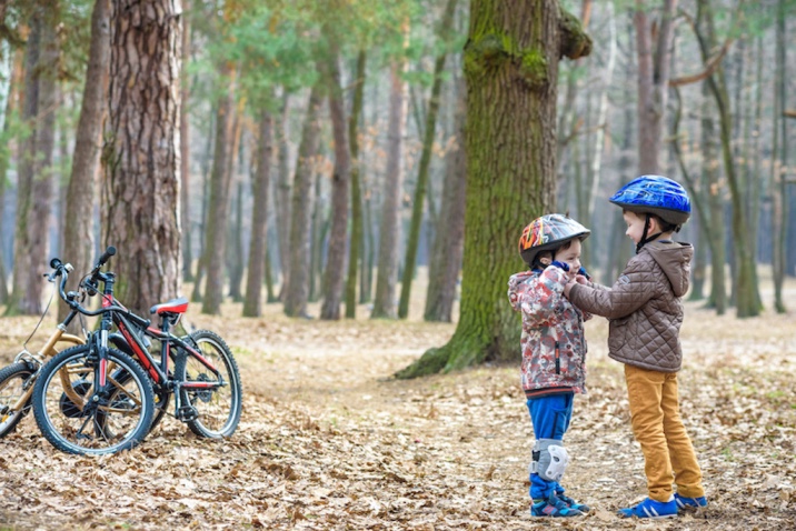 a boy helping his brother wear his helmet- random acts of kindness idea