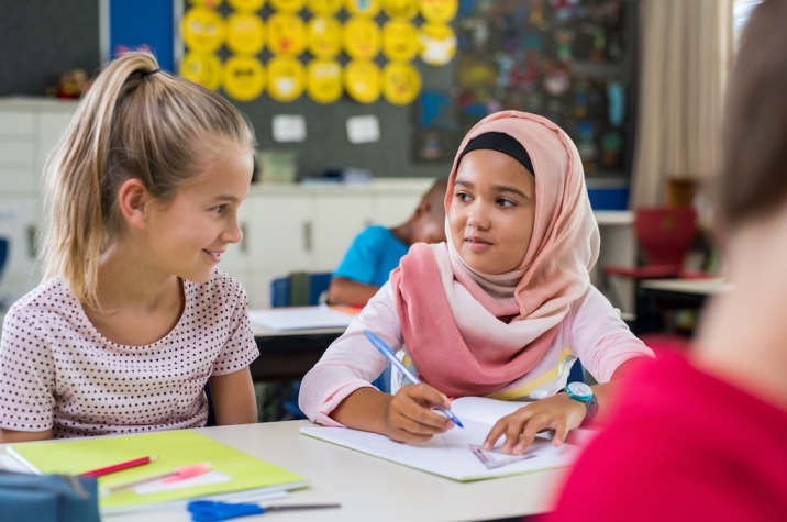 a white girl smiling at a hijabi girl