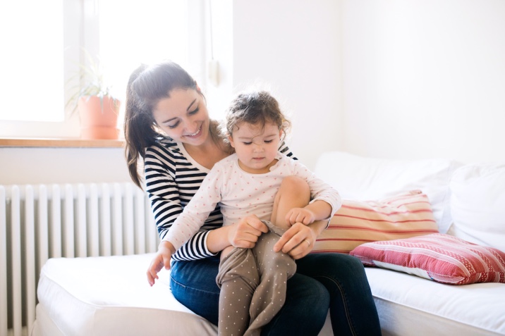 a mom helping her daughter to dress 