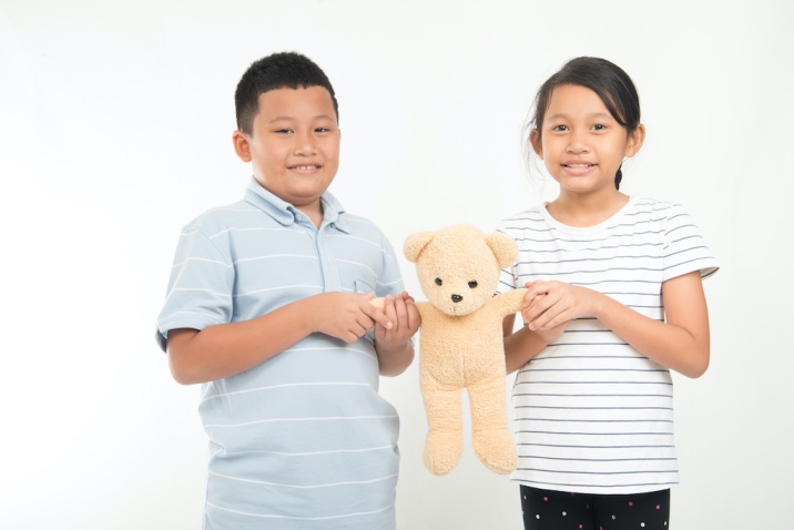 a boy and a girl holding a teddy bear