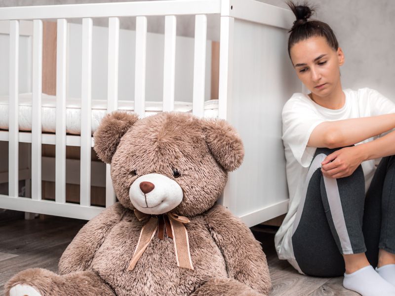 a depressed new mom sitting beside a crib