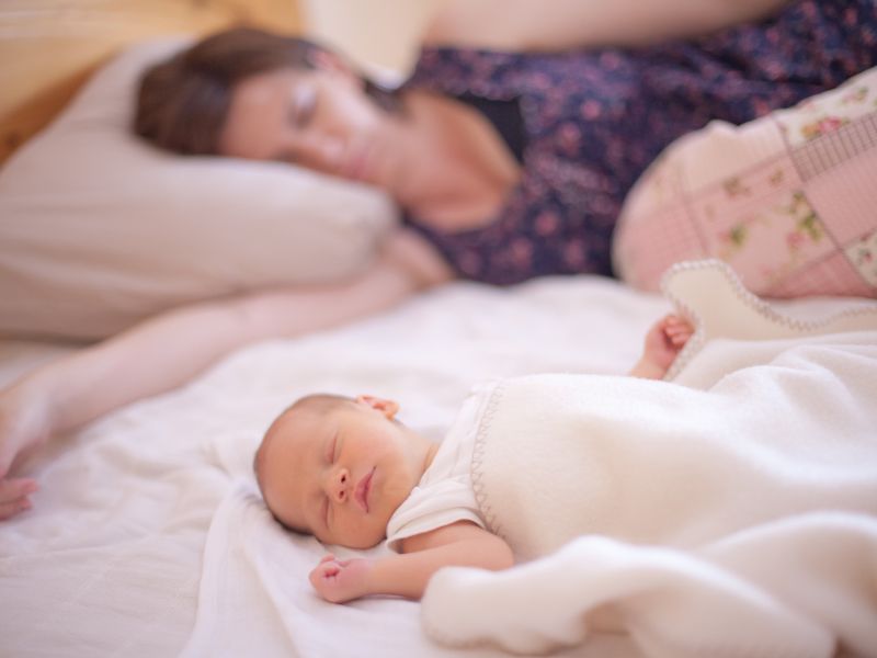 a mom sleeping on a bed with her newborn baby