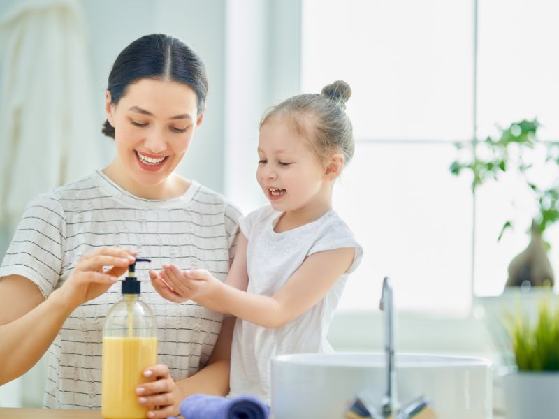 a girl washing her hands with mom