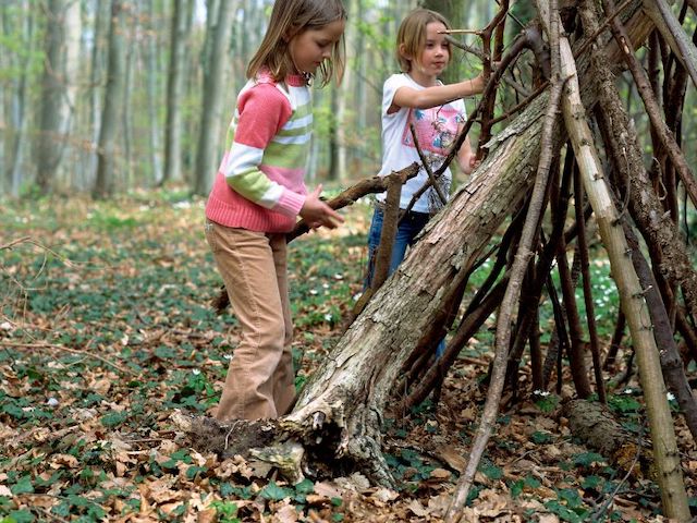 two girls building a fort with branches-nature play for kids