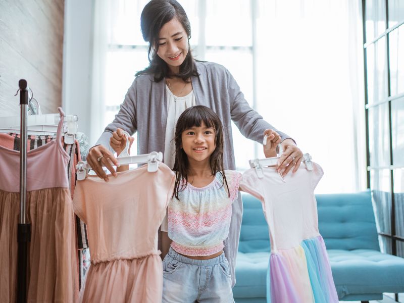 a girl is choosing between her outfits with the help of mom - giving choices to strong-willed kids is important