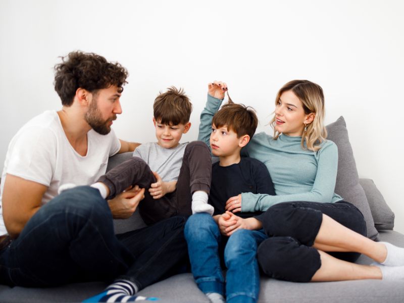 a family of four involved in serious talking. Family meetings are helpful when solving family issues and to raise strong-willed kids who has problem solving skills