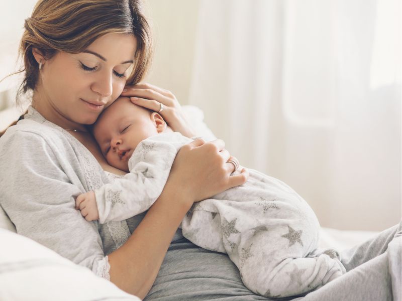 a tired mom with a newborn is resting